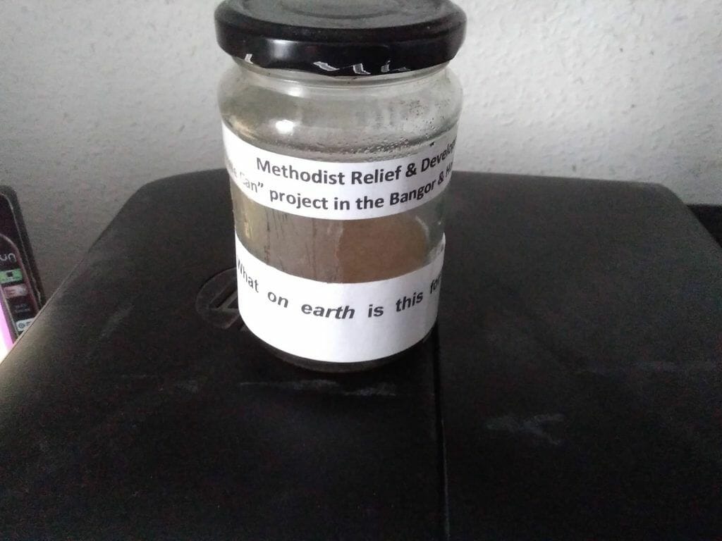 An empty jam jar, pictured on a black table.