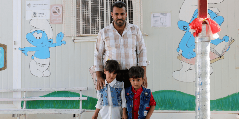 Mohanned stands with his twin children outside the Smurf Centre.